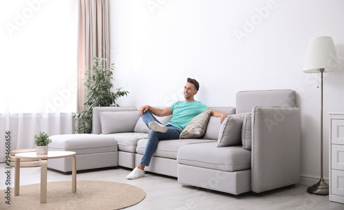 Young man relaxing on sofa under air conditioner at home