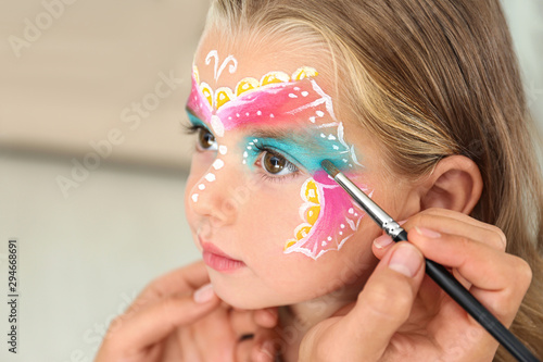 Artist painting face of little girl indoors photo
