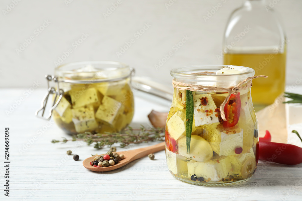 Jar with feta cheese marinated in oil on white wooden table. Pickled food Jar with feta cheese marinated in oil on white wooden table. Pickled food