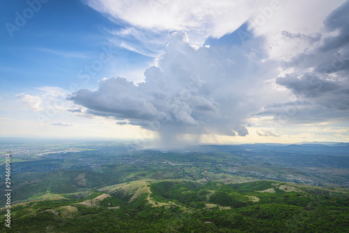 Photograph taken from a mountain of a landscape of the nature where there is a storm in the distance and a cloudy sky