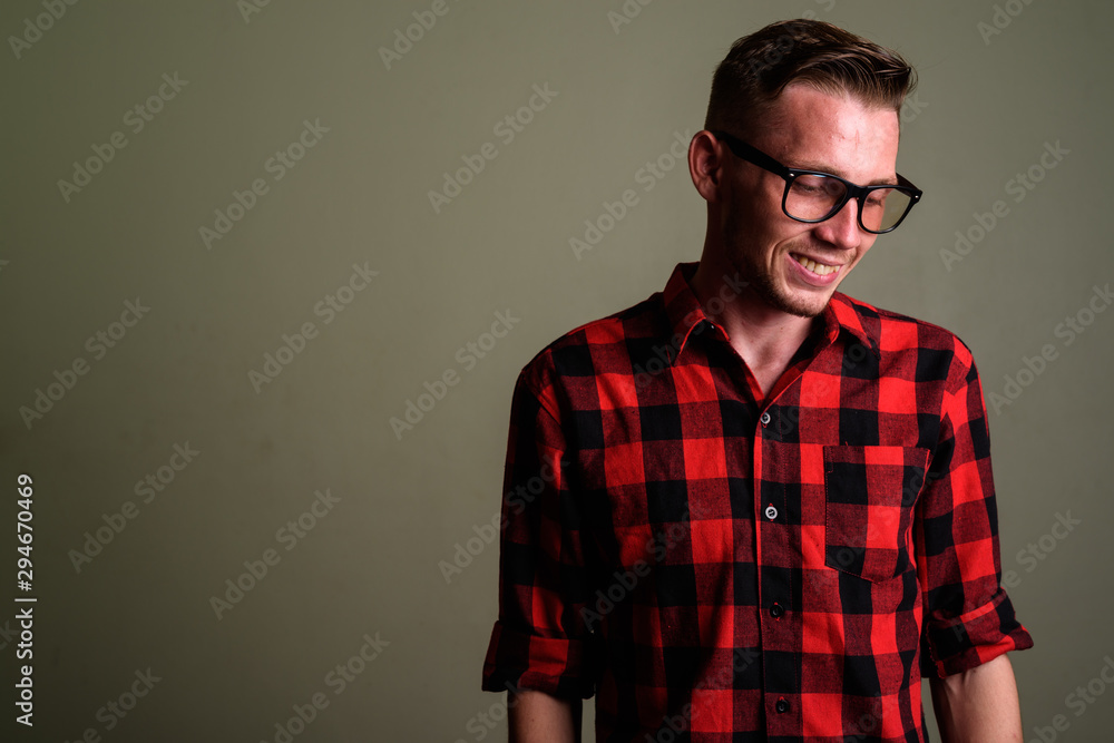 Obraz premium Young man wearing red checkered shirt against colored background