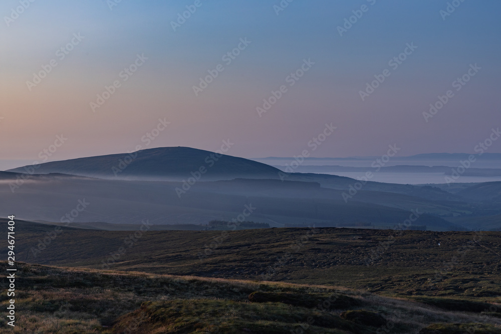 Late evening mists forming around the base of Knocklayd mountain, Ballycastle, County Antrim, Northern Ireland, with Rathlin Island in the distance mountain