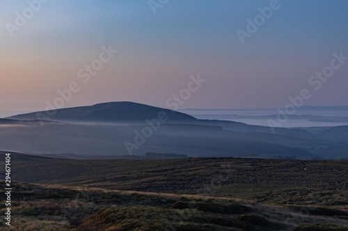 Late evening mists forming around the base of Knocklayd mountain  Ballycastle  County Antrim  Northern Ireland  with Rathlin Island in the distance mountain