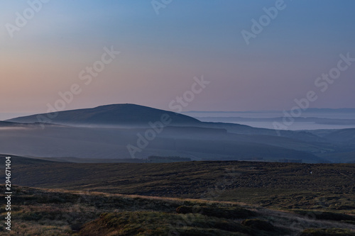 Late evening mists forming around the base of Knocklayd mountain, Ballycastle, County Antrim, Northern Ireland, with Rathlin Island in the distance mountain