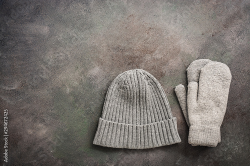 Knitted gray hat and woolen mittens on a dark rustic background. Top view, flat lay,copy space