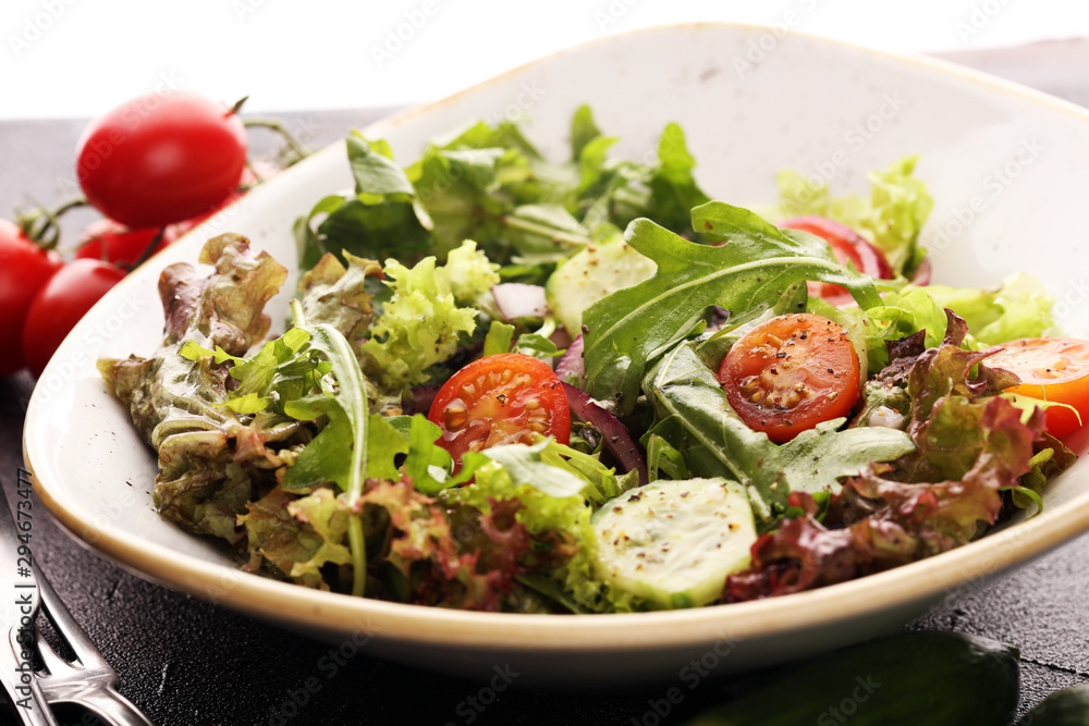 bowl of salad with vegetables and greens, with tomato, cucumber and onions on rustic table bowl of salad with vegetables and greens, with tomato, cucumber and onions on rustic table