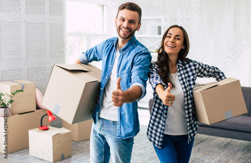 Thumbs up. A young family couple proves that everything is going great with their relocation by putting the thumbs up and smiling widely.