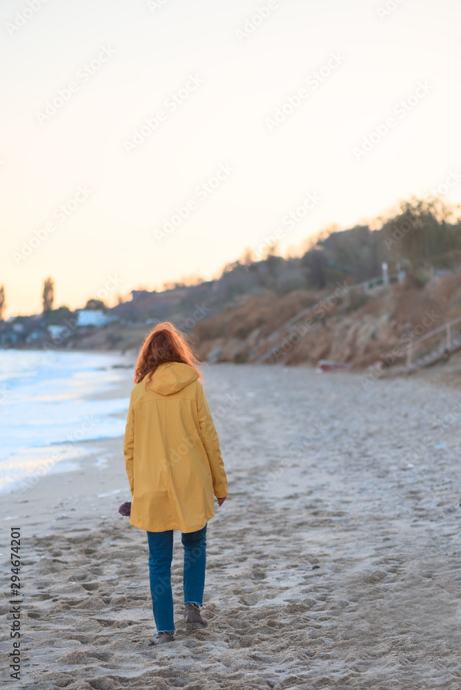 Great pleasure. Charming calm young woman is standing near sea with closed eyes and expressing delight. She is posing against wonderful sunset while enjoying last rays of the sun