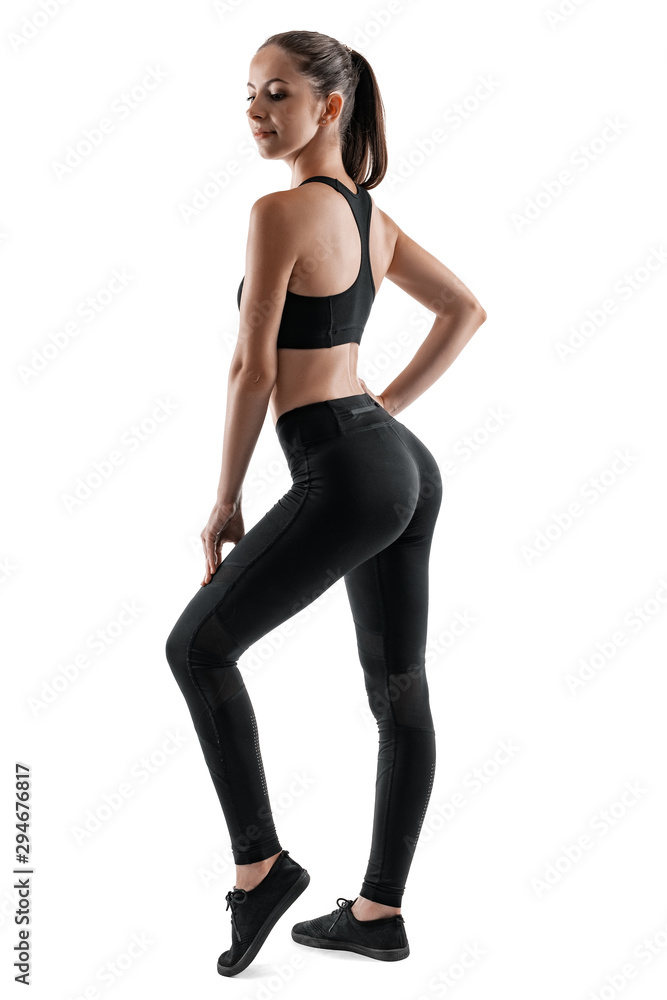 Brunette woman in black leggings, top and sneakers is posing