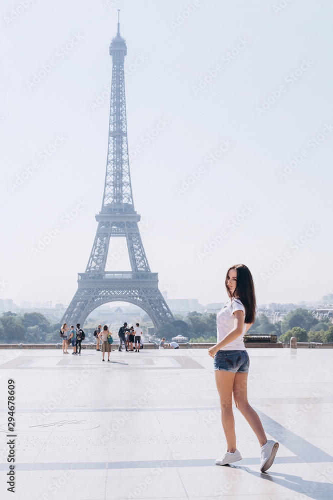 Woman tourist at Eiffel Tower smiling. Beautiful European young girl enjoying vacation in Paris, France. Travel concept.