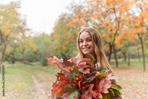 beautiful blonde with an armful of leaves in autumn park