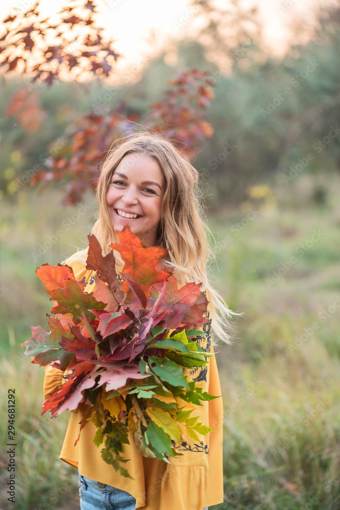 Beautiful woman with long blonde hair an armful of leaves in autumn park Beautiful woman with long blonde hair an armful of leaves in autumn park