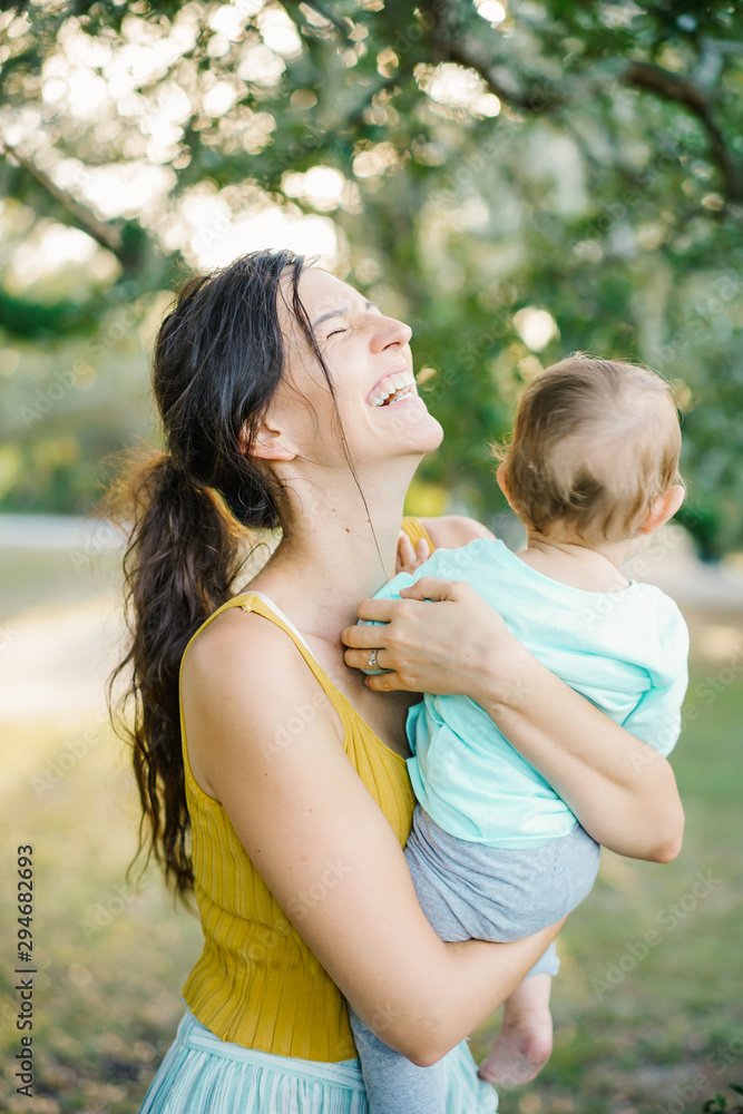 Laughing mother hugging baby in countryside Laughing mother hugging baby in countryside