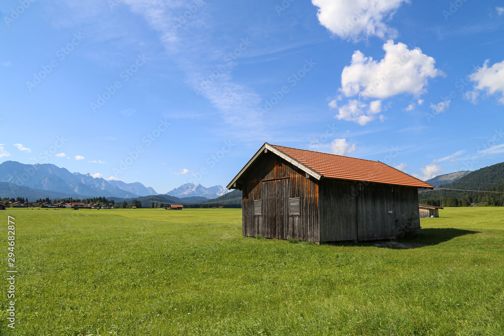 Mountain huts on green meadows in the Alps