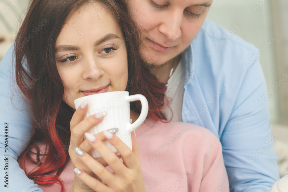 Young happy couple in love in the morning in bed with cups of coffee having Breakfast. Young happy couple in love in the morning in bed with cups of coffee having Breakfast.