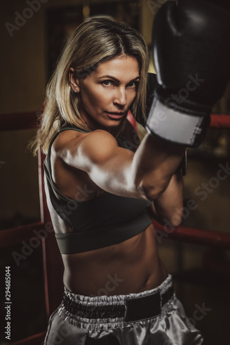 Focused muscular woman has her boxing training wearing boxing gloves.