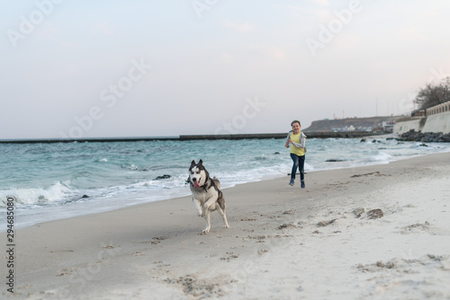 Boy playing with husky dog in collar on the beach