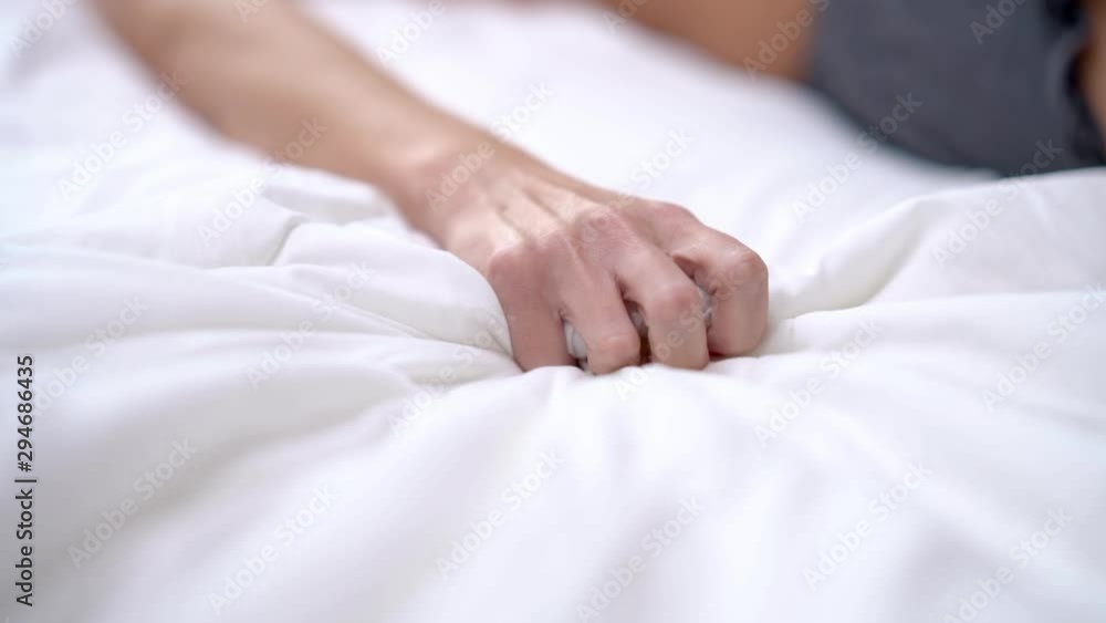 Woman's hand squeezing white sheet in erotic excitement Woman's hand squeezing white sheet in erotic excitement