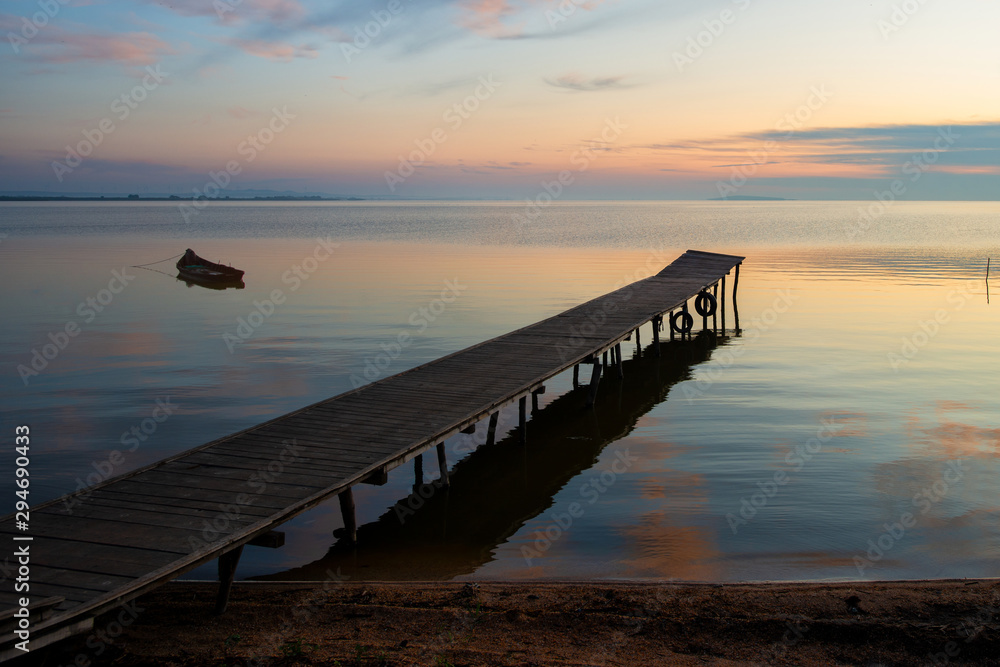 Obraz premium beautiful sunrise over water and silhouette of fishing boat