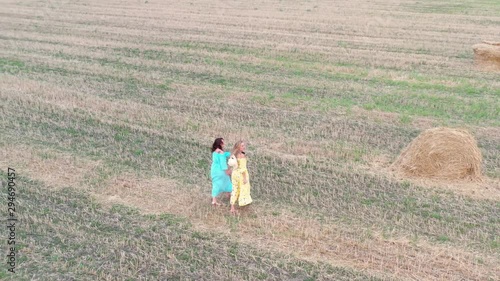 Wallpaper Mural Two girl are walking in dress on field with sheaves of hay at sunset. Aerial view of field Torontodigital.ca