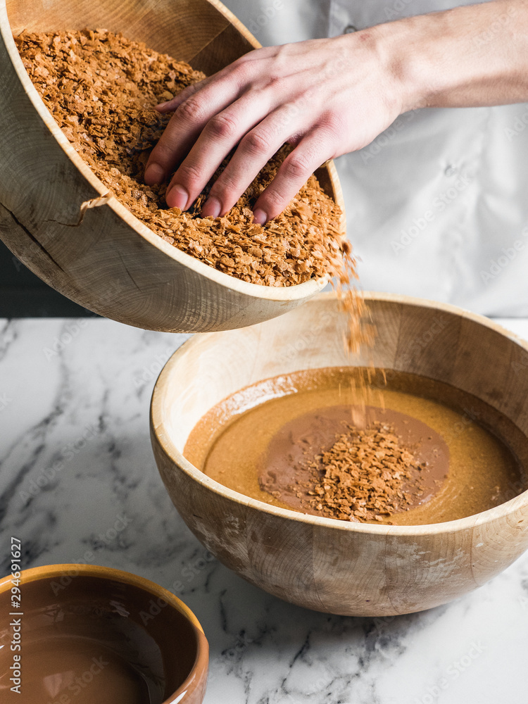 Confectioner adding crunchy filling to chocolate Confectioner adding crunchy filling to chocolate