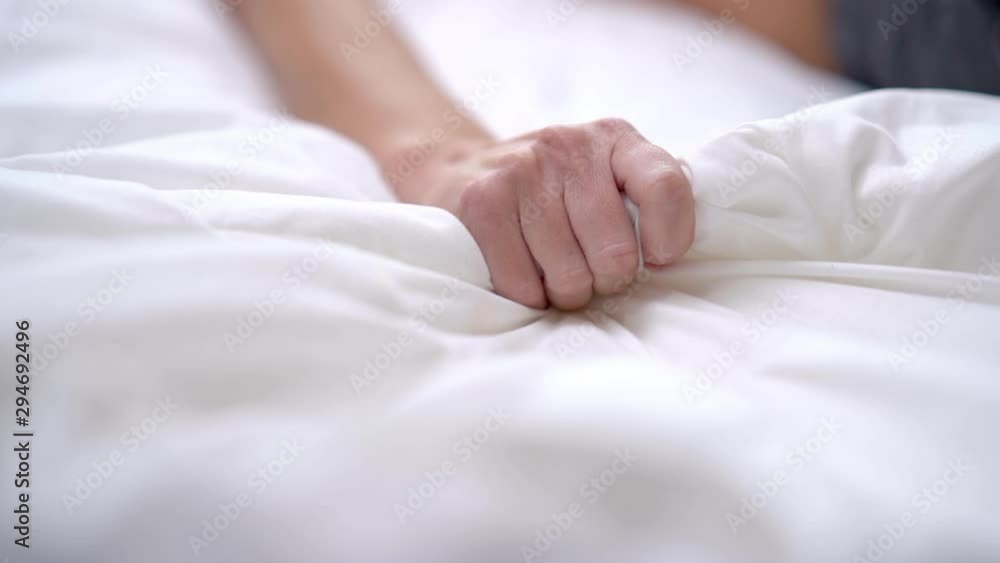 Woman's hand squeezing white sheet in erotic excitement Woman's hand squeezing white sheet in erotic excitement