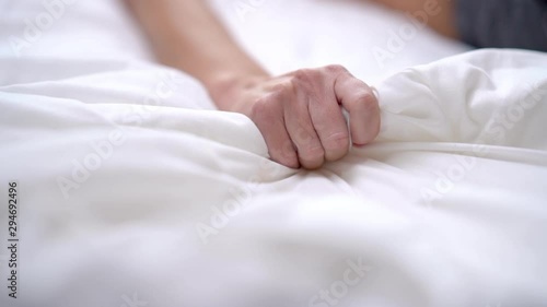 Woman's hand squeezing white sheet in erotic excitement