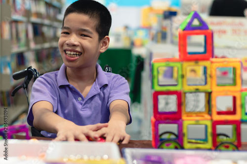 Disabled child on wheelchair is interested in skills development toys in Books and toys fair,Special children's lifestyle,Life in the education age of special need kids,Happy disability kid concept.