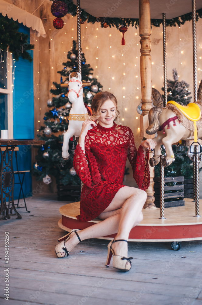 Obraz premium Beautiful young woman rejoices near a carousel with horses. Christmas.