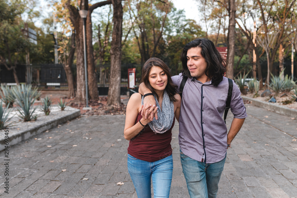 Ethnic couple walking giving a hug each other in park Ethnic couple walking giving a hug each other in park