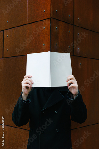 Man with book at face level near building photo