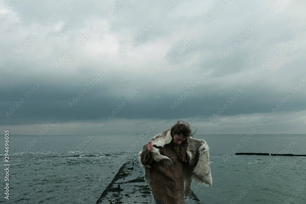 portrait of a guy in animal skin and burlap against the background of the sea and sky portrait of a guy in animal skin and burlap against the background of the sea and sky