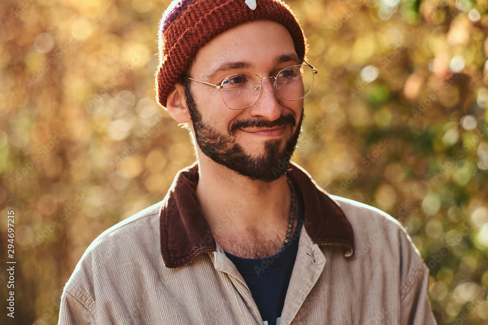 Portrait of attractive young student in hat and glasses with yellow autumn trees at background. Portrait of attractive young student in hat and glasses with yellow autumn trees at background.