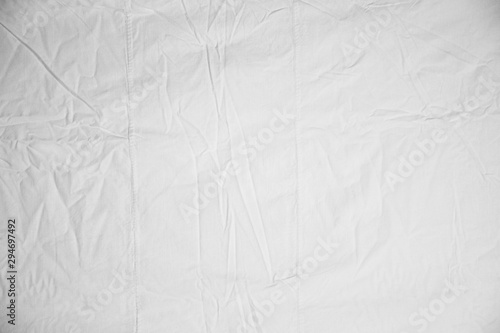 White Crumpled Bed Sheet Background Texture. white fabric top view. pleats on light fabric