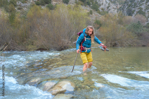 Barefoot Woman crossing a cold mountain river photo