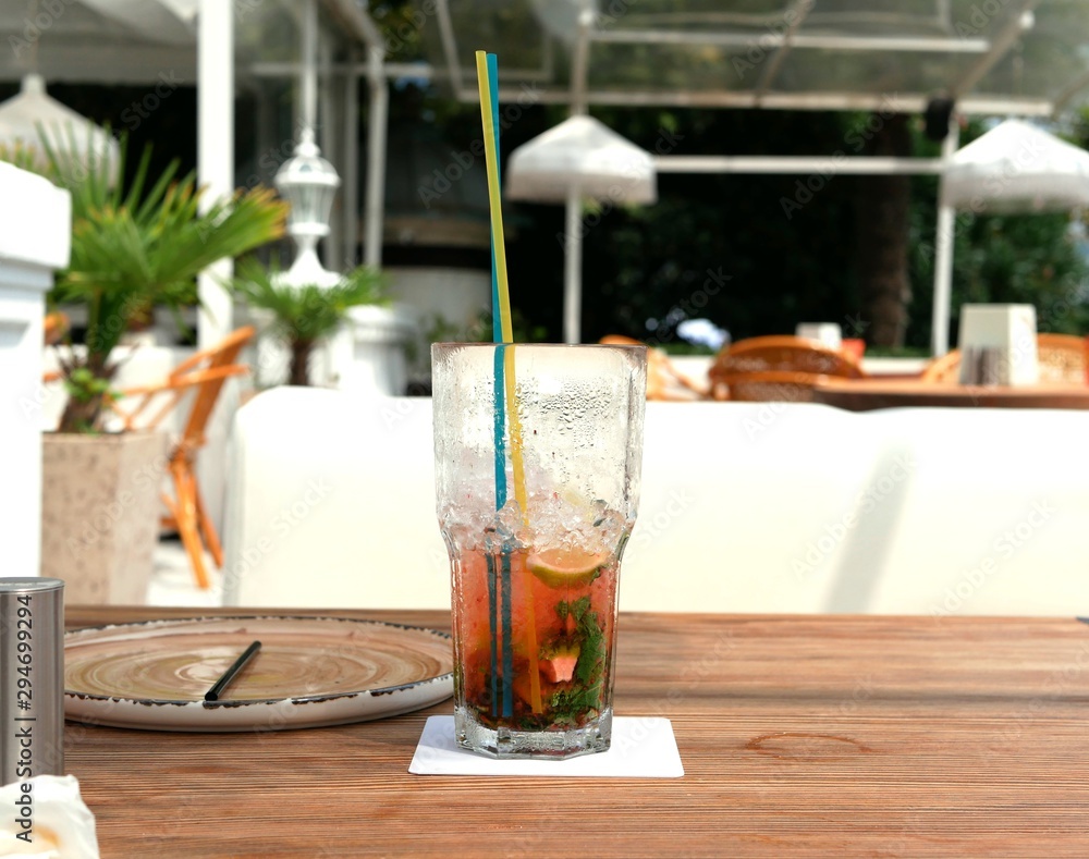 Two glasses of cold mojitos and an iced strawberry cocktail sit on a table on the cafe's summer veranda. Glasses with a tube covered with droplets of condensate. Refreshing drinks on a hot summer day. Two glasses of cold mojitos and an iced strawberry cocktail sit on a table on the cafe's summer veranda. Glasses with a tube covered with droplets of condensate. Refreshing drinks on a hot summer day.