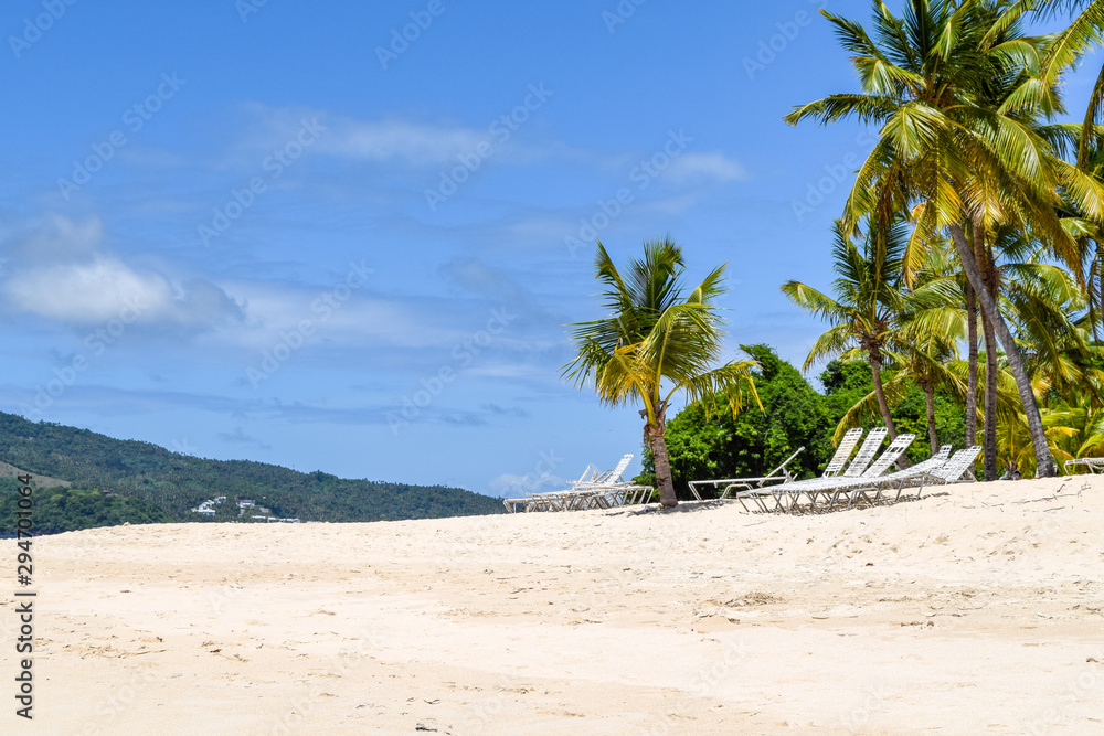 Beach with palms and white sand and deck chairs in front of the ocean, caribbean island cayo levantado