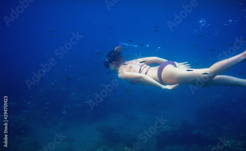 Woman swimming in blue water. Female snorkel underwater photo. Freediver in blue seawater of tropical lagoon.