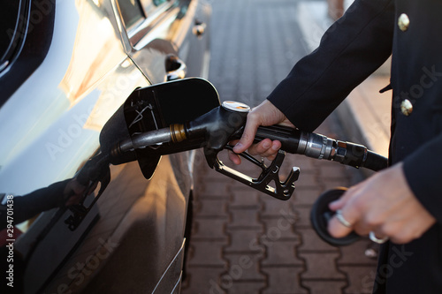 Closeup hand holding fuel nozzle to refuel oil for car in gas station