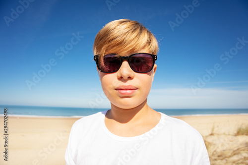 Handsome boy in sunglasses close portrait on beach