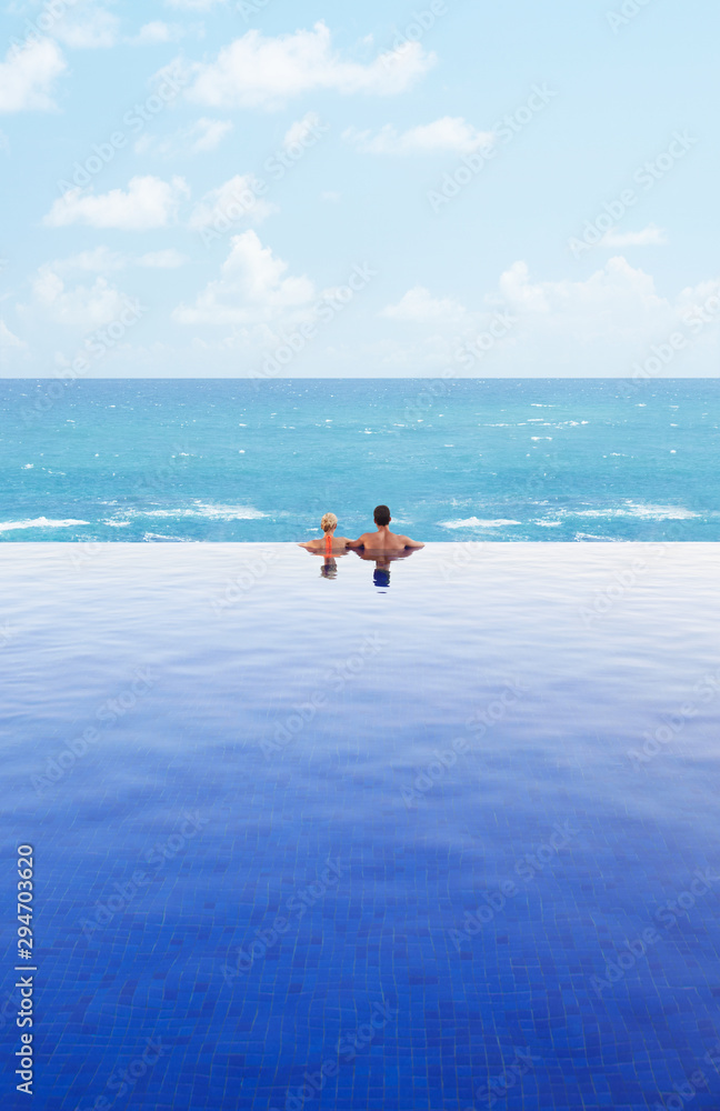 Romantic couple looking at the ocean from infinity pool Romantic couple looking at the ocean from infinity pool