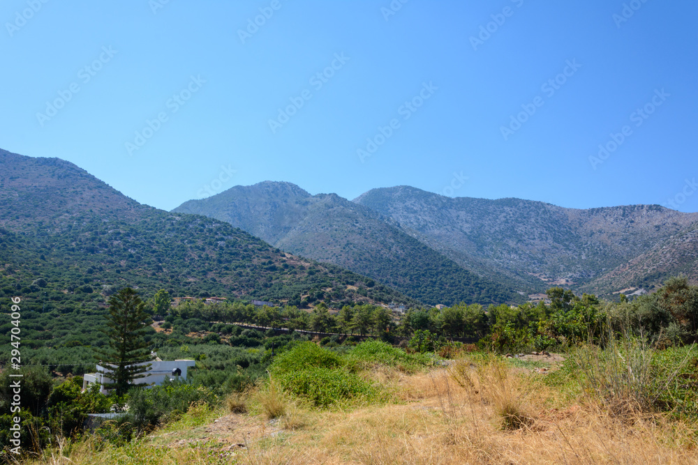 view from the hill to the mountain range, the road and the clear blue sky. Crete, Greece