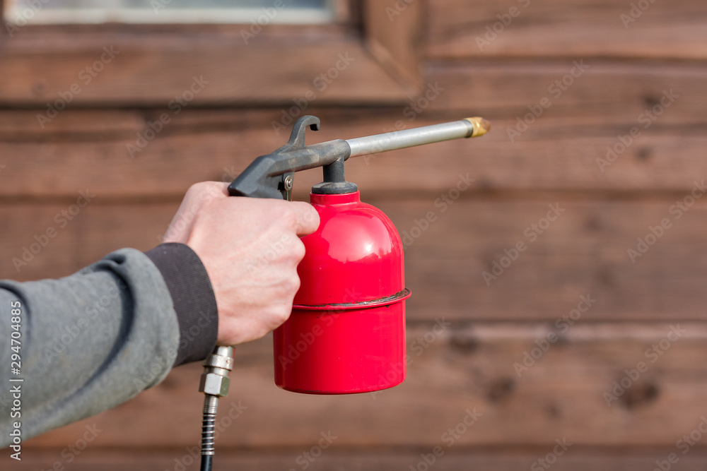 Naklejka premium Initial treatment of wooden buildings with a protective coating using a spray gun