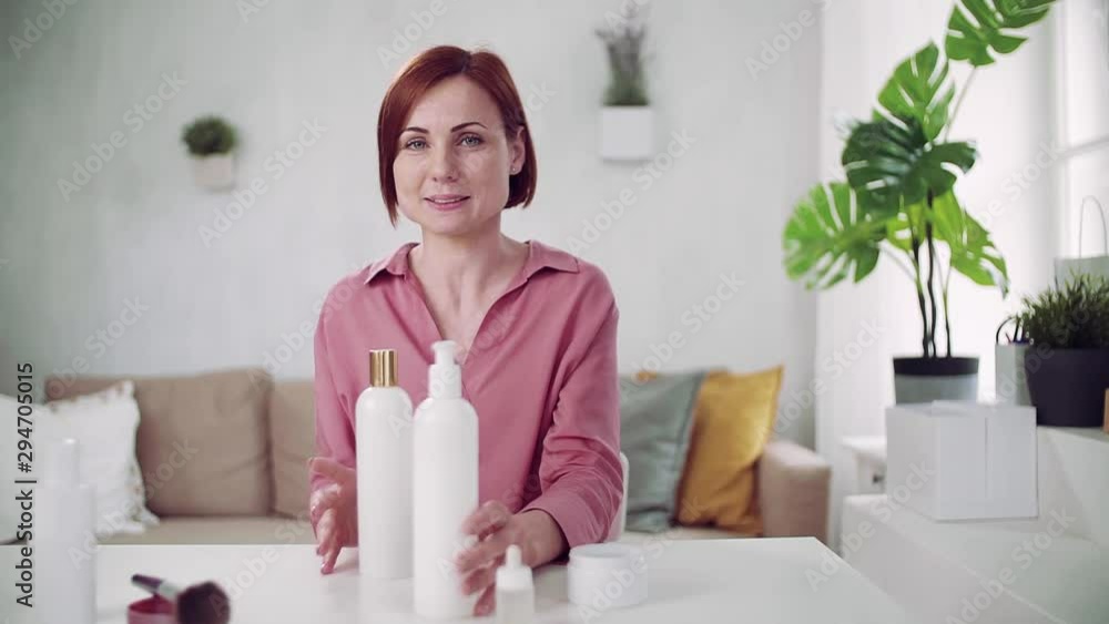 Front view of young woman vlogger indoors, making video about beauty products. Front view of young woman vlogger indoors, making video about beauty products.