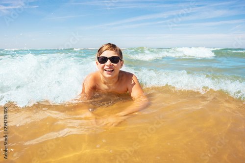 Boy have fun in sea waves laying on sand beach © Sergey Novikov