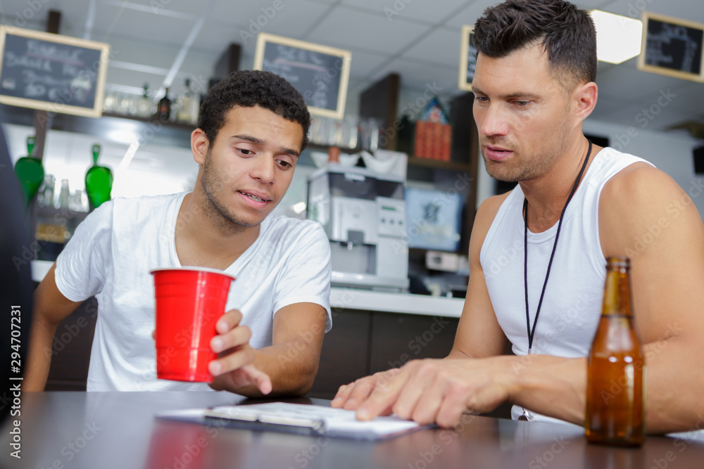 two men in bar watching football and drinking beer two men in bar watching football and drinking beer
