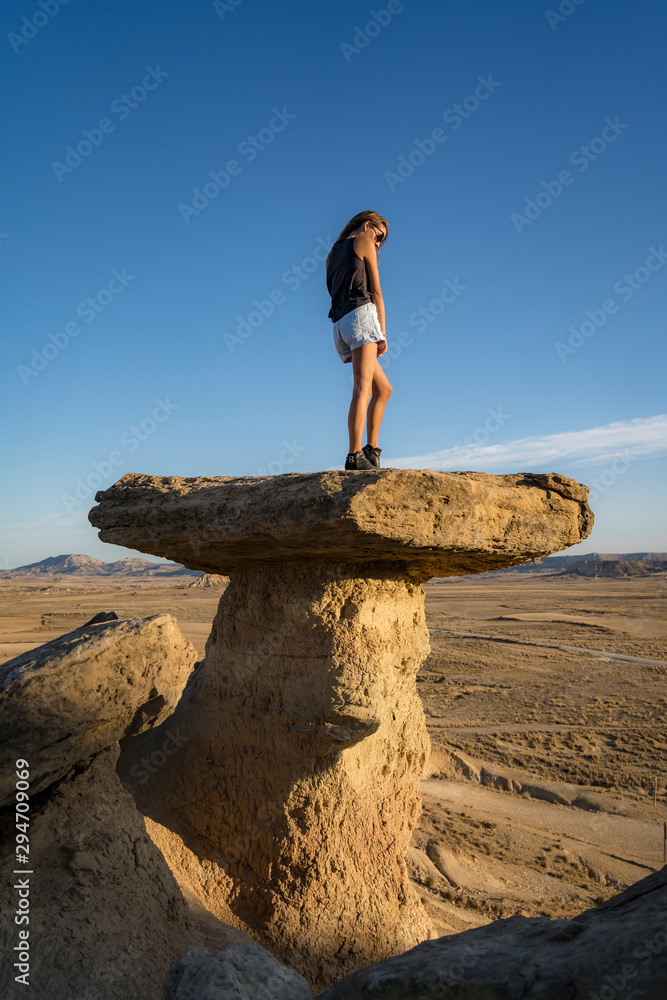Lifestyle of a young blonde with rocker outfit on top of a beautiful desert stones