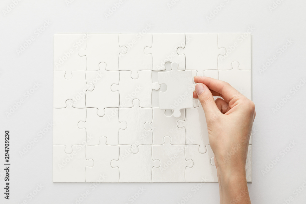 cropped view of woman completing jigsaw puzzle on white background cropped view of woman completing jigsaw puzzle on white background