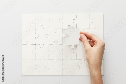 cropped view of woman completing jigsaw puzzle on white background