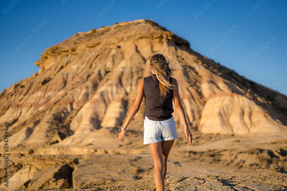 A young blonde with outfit rocker with her arms wide open in the desert of the Bardenas Reales, Navarra. Spain